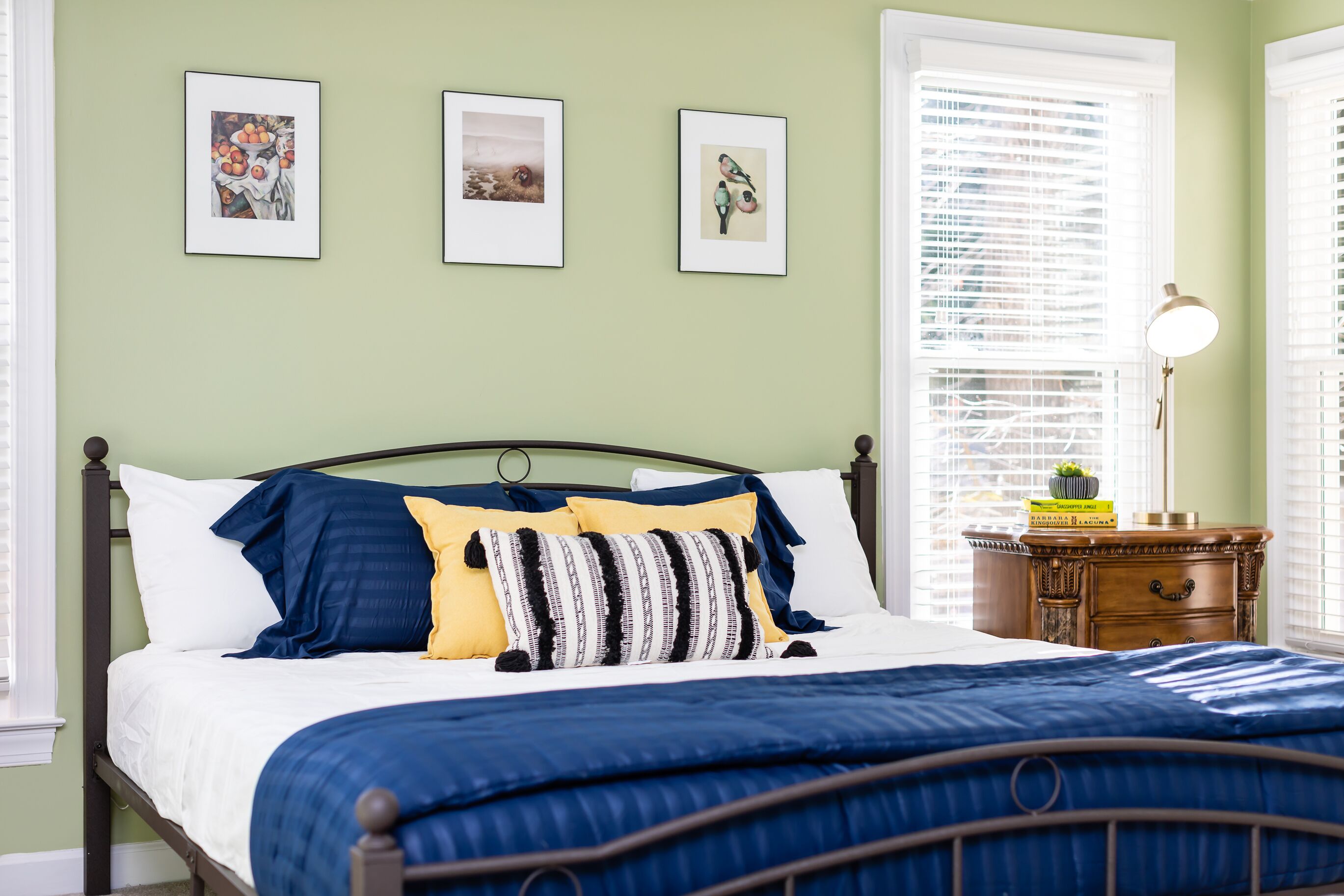 A bedroom with a bed, a nightstand, and a window with blinds.