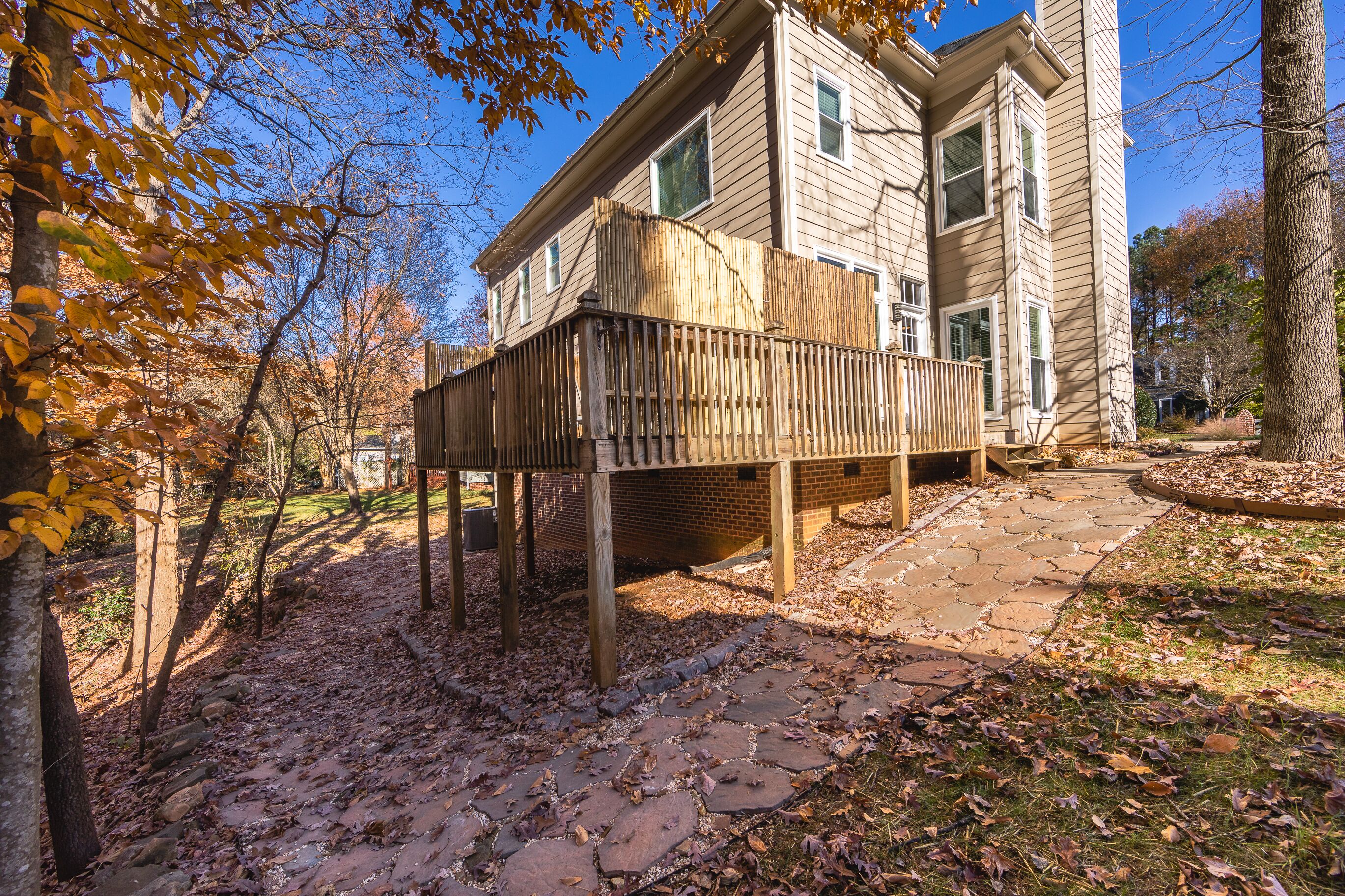 A two-story house with a wooden deck and brick foundation.