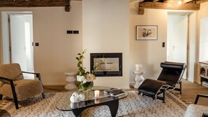 A living room with a fireplace, a sofa, a chair, and a coffee table. - Gîte la Porterie - Clos des Dames de Lancharre (Chapaize)