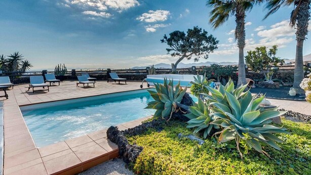 Zona piscina con lettini, un albero e vista sul paesaggio.