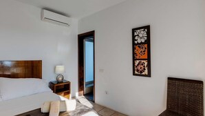 Camera da letto con un letto, comodino, lampada e un'opera d'arte appesa al muro.