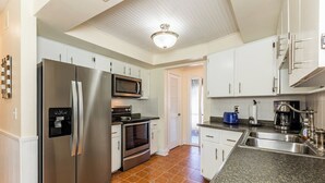 Una cocina moderna con electrodomésticos de acero inoxidable, armarios blancos y una encimera de granito.