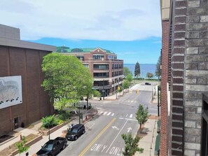 A street view with a building featuring a green roof and a brick facade.
