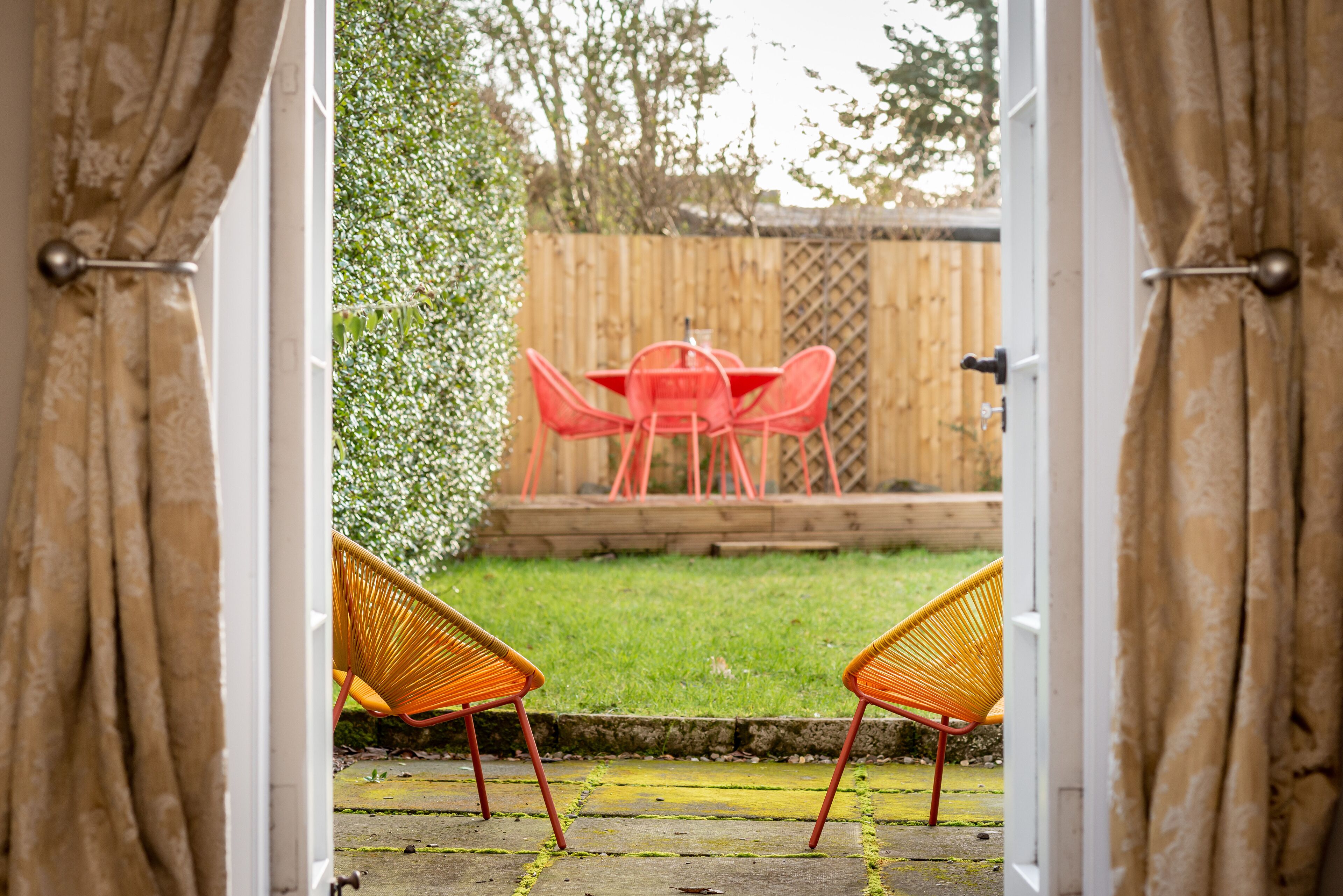 An open doorway leading to a patio with a wooden table and chairs.