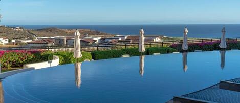 A infinity pool with a view of the ocean and a coastal town.