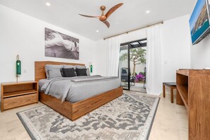 A bedroom with a bed, a ceiling fan, a desk, and a view of the outdoors.