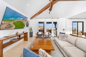 A spacious living room with a large painting, wooden furniture, and a view to the outside. - Quivira Ocean view private villa with pool (Cabo San Lucas)
