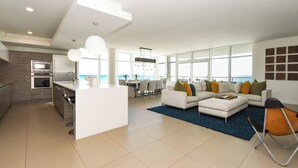A modern living space with a kitchen, dining area, and seating area with a view. - Luxurious Beachfront Condo w/ Beach Service & Rooftop Pool in Destin! 🌊☀💙 (Destin)