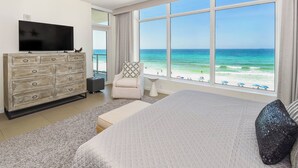 A bedroom with a large bed, a TV, a dresser, and a view of the ocean. - Luxurious Beachfront Condo w/ Beach Service & Rooftop Pool in Destin! 🌊☀💙 (Destin)