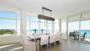 A spacious dining area with a large table, white chairs, and a hanging light fixture. - Luxurious Beachfront Condo w/ Beach Service & Rooftop Pool in Destin! 🌊☀💙 (Destin)