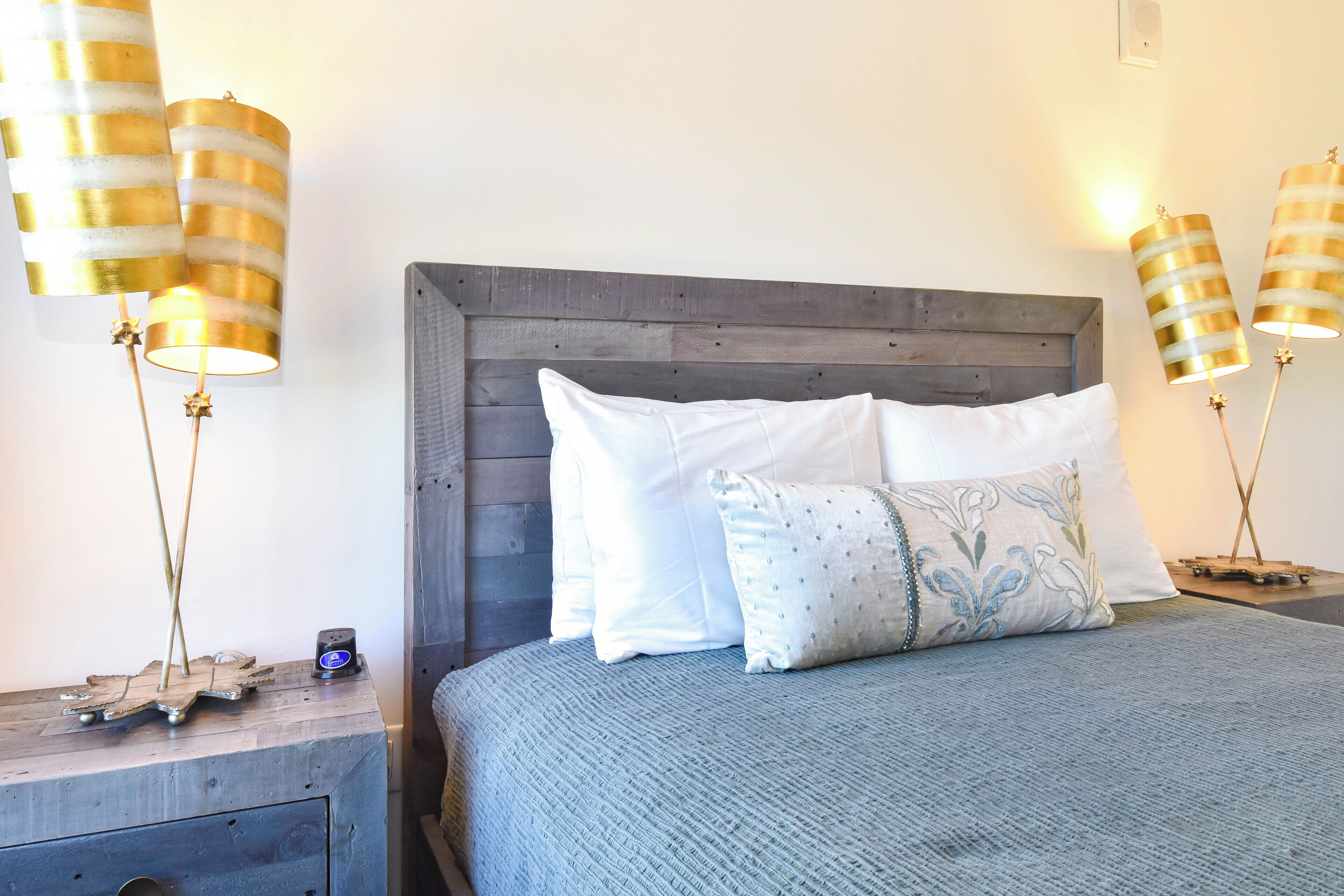 A bed with a wooden headboard, two bedside tables with lamps, and a small decorative item on the nightstand.