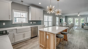 Una cocina moderna con armarios blancos, una isla central con taburetes e iluminación colgante.