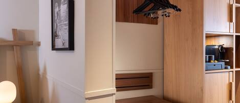 A compact bathroom with a wooden vanity, a hanging clothes rack, and a framed picture on the wall.