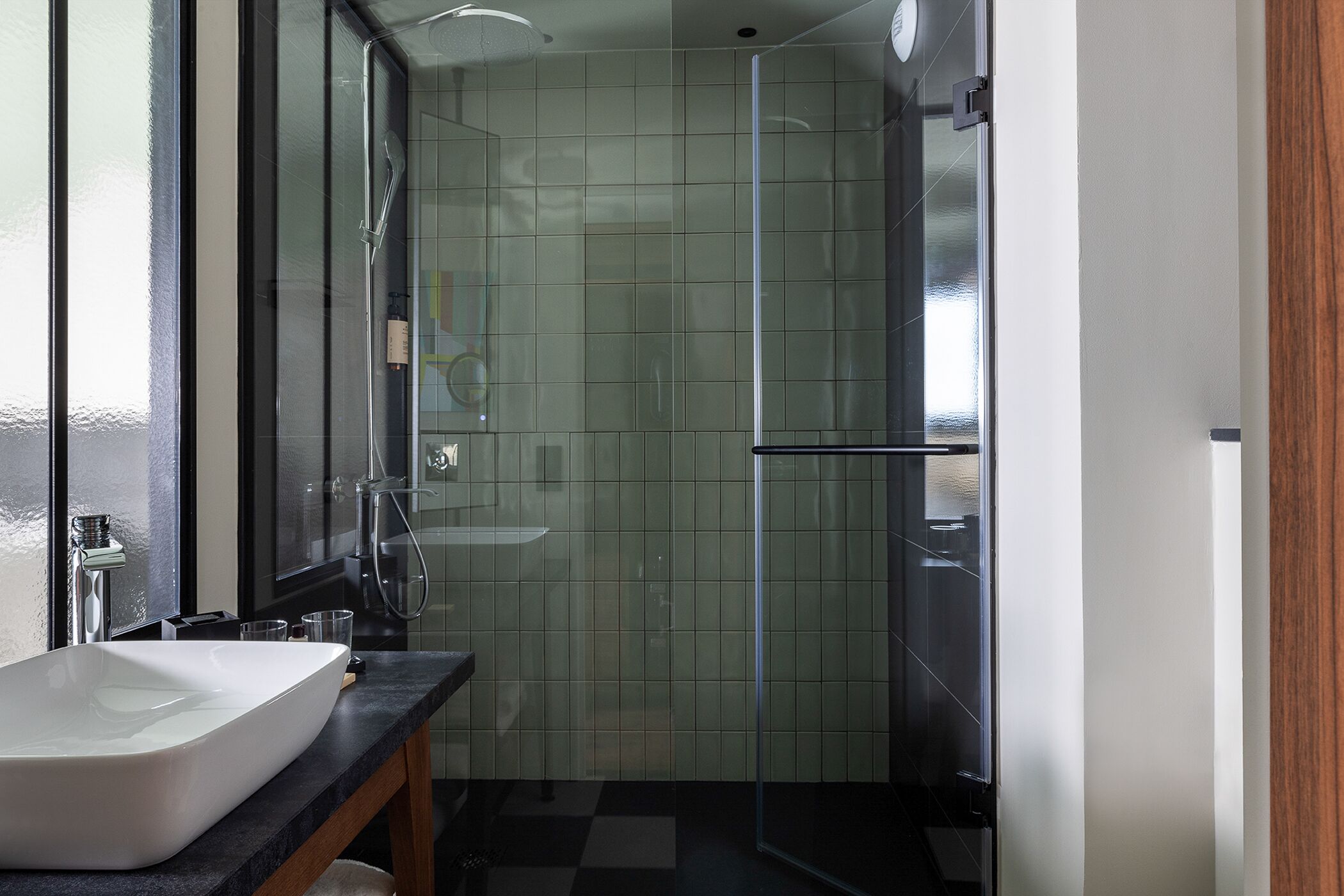 Une salle de bain moderne avec un grand lavabo blanc, une douche en verre et un comptoir noir.