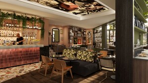 Zona de bar moderna con un cantinero, un espacio de estar con un sofá y sillones, y una estantería llena de libros y adornos.