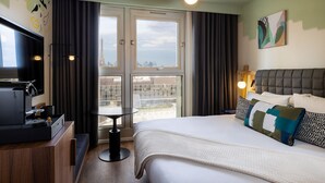 Habitación de hotel con cama, televisión, cafetera, mesa y vistas a la Torre Eiffel.