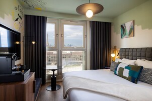 Habitación de hotel con cama, televisión, cafetera, mesa y vistas a la Torre Eiffel.