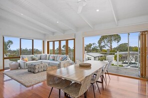 A spacious living area with a large window, a sofa, a dining table, and a view of the outdoors.