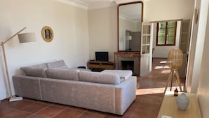A living room with a sofa, a television, a fireplace, a mirror, and a table with a candle.