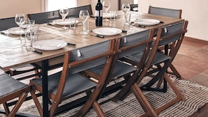 A dining room with a long wooden table set for six, surrounded by dark wooden chairs.