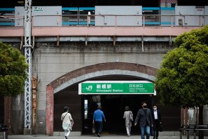 Ein Bahnhofseingang mit einem grünen Schild, das 'Shimbashi Station' und 'Hibiya Entrance' anzeigt.