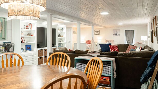 A cozy living room with a wooden dining table, chairs, a brown sofa, and a large woven light fixture. - POOL, HOT TUB, PET FRIENDLY FENCED IN YARD RETREAT CLOSE TO LAKE MICHIGAN!!! (Coloma)