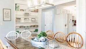 A dining area with a glass-top table, wooden chairs, and a chandelier. - POOL, HOT TUB, PET FRIENDLY FENCED IN YARD RETREAT CLOSE TO LAKE MICHIGAN!!! (Coloma)