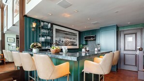 Een moderne keuken met een centraal eiland, een aantal barkrukken en een groot, ingelijst schilderij.