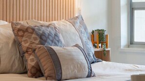 Una camera da letto con un letto, cuscini a fantasia, un lampadario a parete e una finestra.