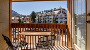 Un balcone con ringhiera in legno, un tavolo con sedie e vista su edifici a più piani con balconi.
