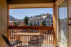 Un balcon doté d’une balustrade en bois, une table avec des chaises et une vue sur des immeubles à plusieurs étages, eux aussi dotés de balcons.