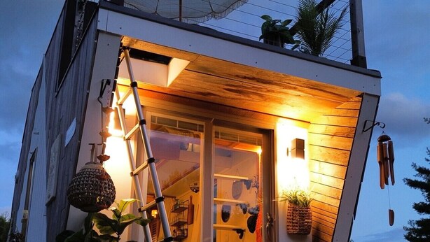 Una casa moderna con techo inclinado, una escalera y un paraguas grande.
