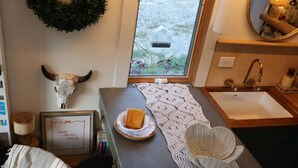 Una cocina acogedora con vista a un jardín, un espejo redondo, una cita enmarcada y un adorno rústico.