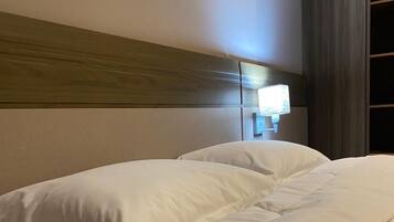 Habitación de hotel con una cama grande, cabecera de madera y una lámpara fijada a la pared.