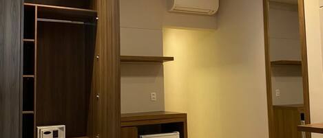 Un dormitorio con cama, armario, mesita de noche pequeña y aire acondicionado.