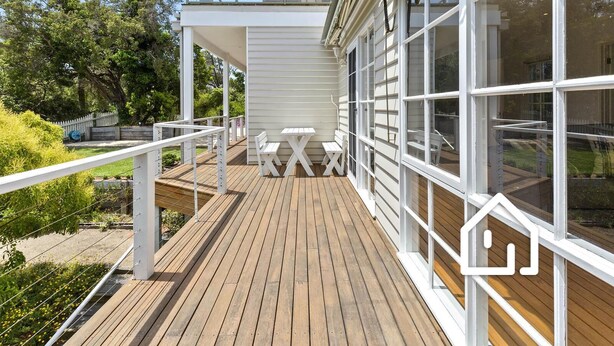 Une terrasse en bois avec des rampes blanches, une table et des bancs.
