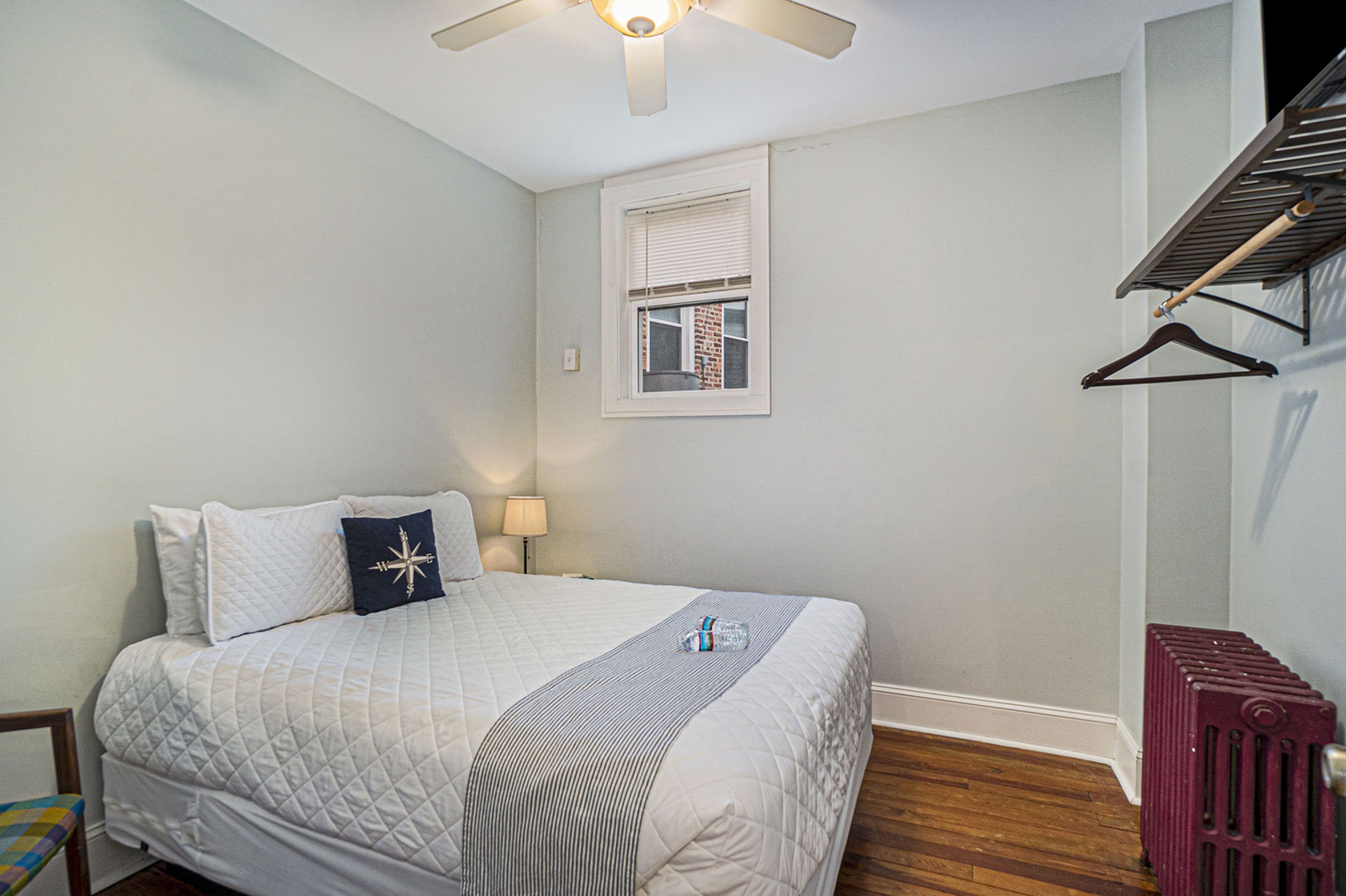Une chambre à coucher avec un lit, une fenêtre, un radiateur et un ventilateur de plafond.