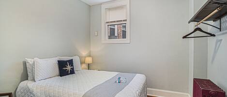 Une chambre à coucher avec un lit, une fenêtre, un radiateur et un ventilateur de plafond.