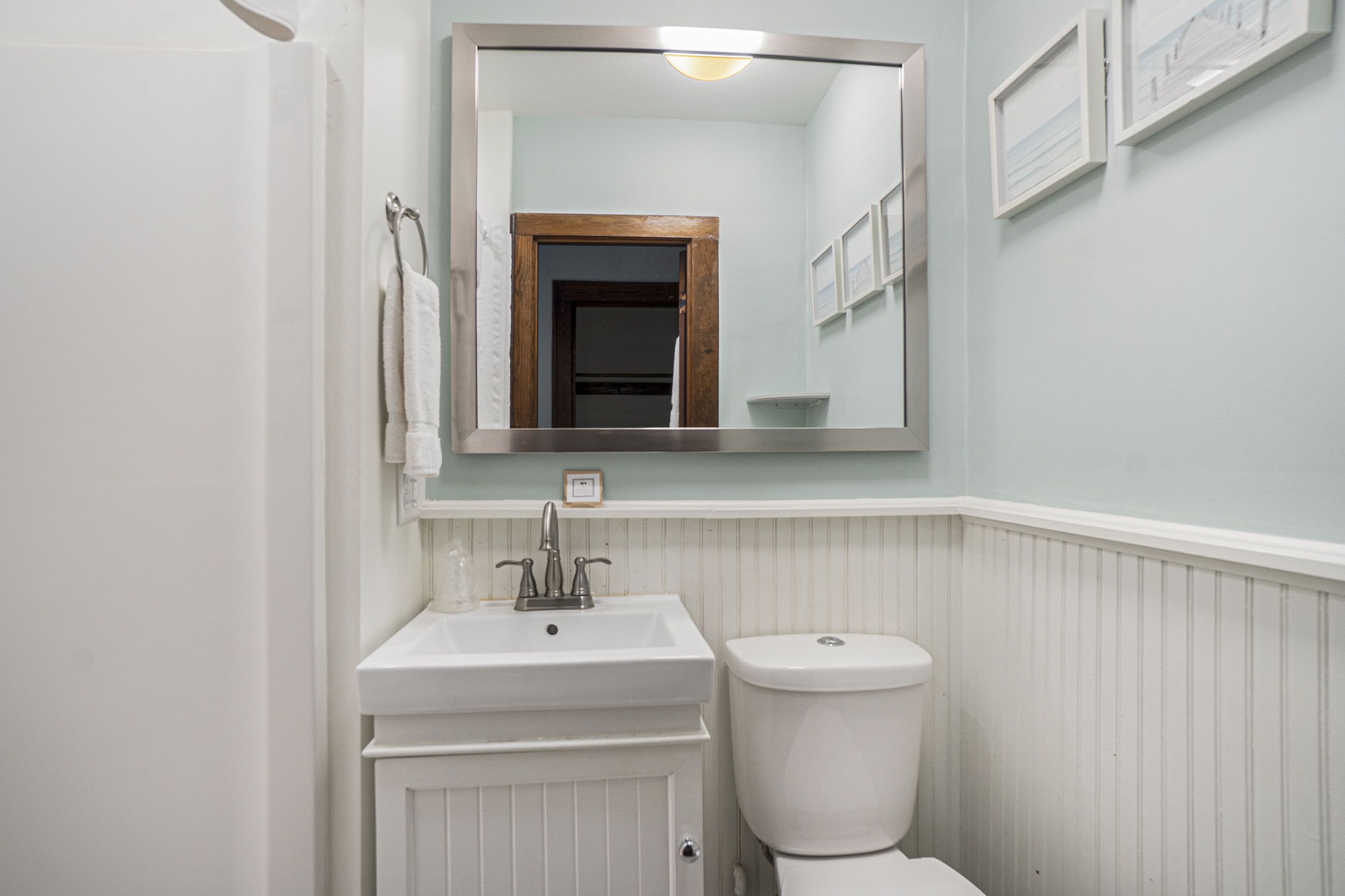A bathroom with a white sink, a mirror, and a toilet.