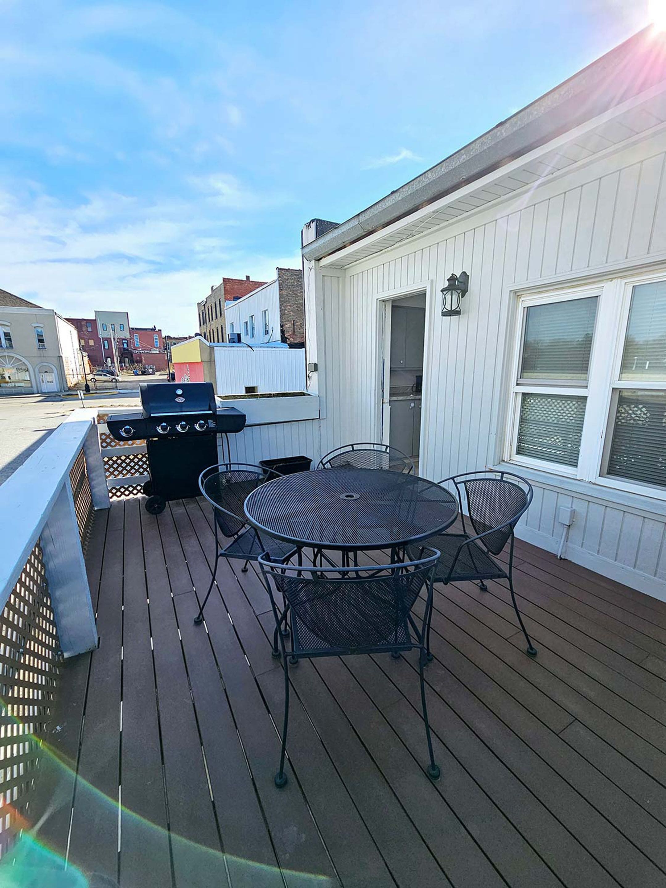 Eine Terrasse mit Grill, rundem Tisch und Stühlen.