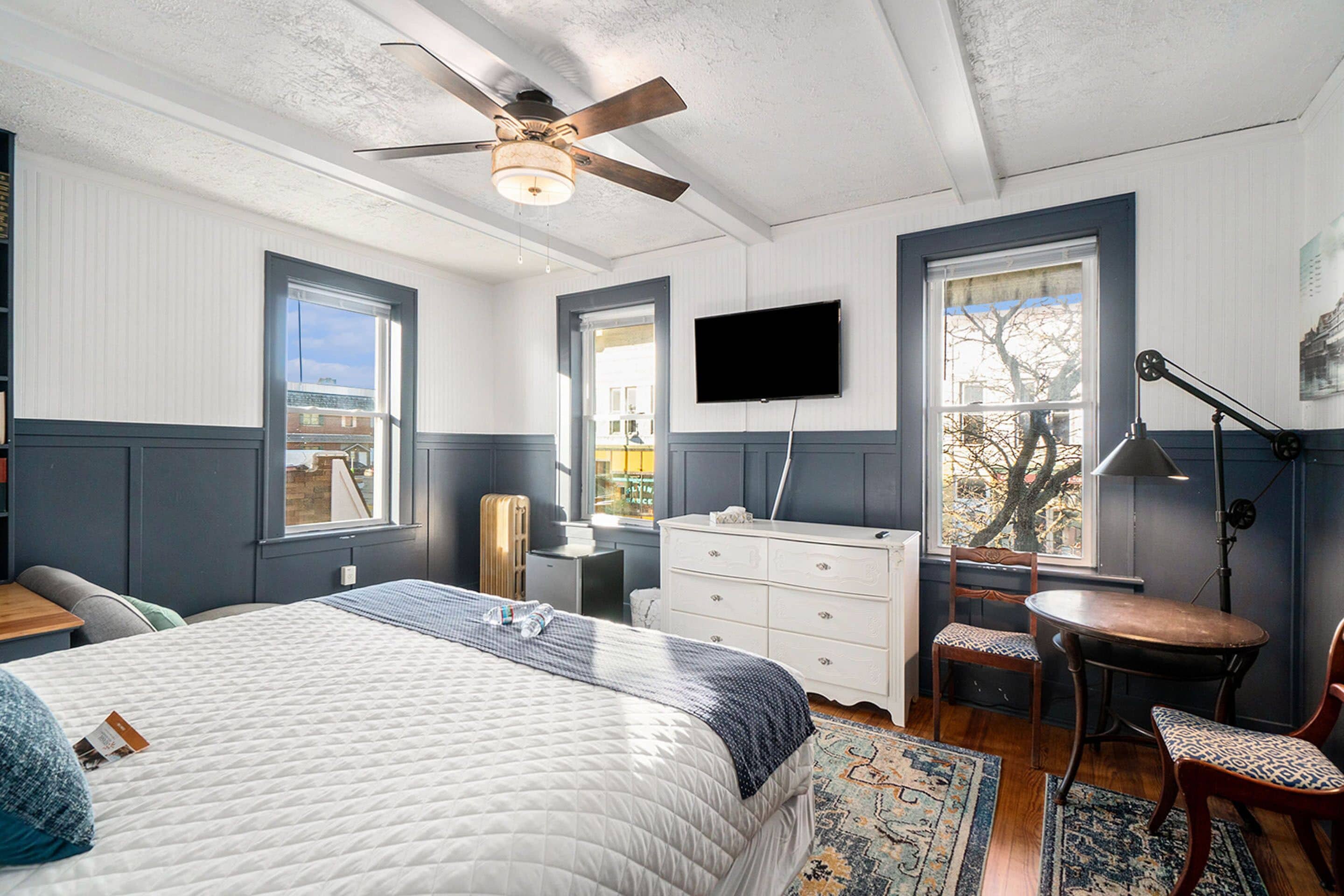A bedroom with a bed, dresser, chair, desk, and TV.