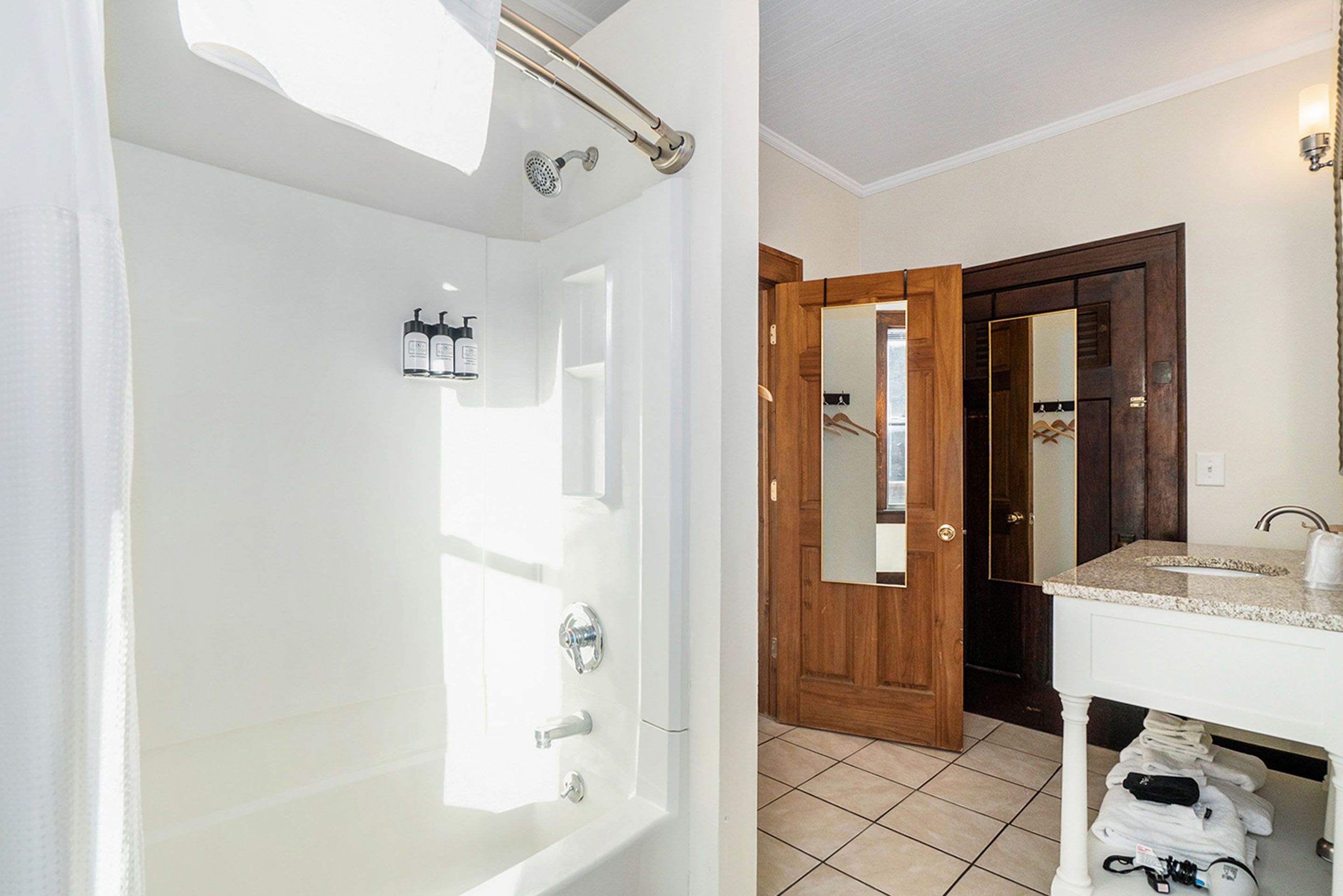 A bathroom with a bathtub, a wooden door, and a vanity with a sink.