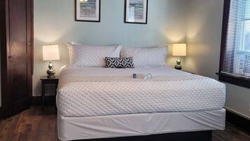 A bedroom with a large bed, two bedside lamps, a wooden ceiling, and two framed pictures on the wall.
