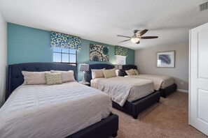 Two beds with dark headboards and light bedspreads, ceiling fan, and wall lamps.
