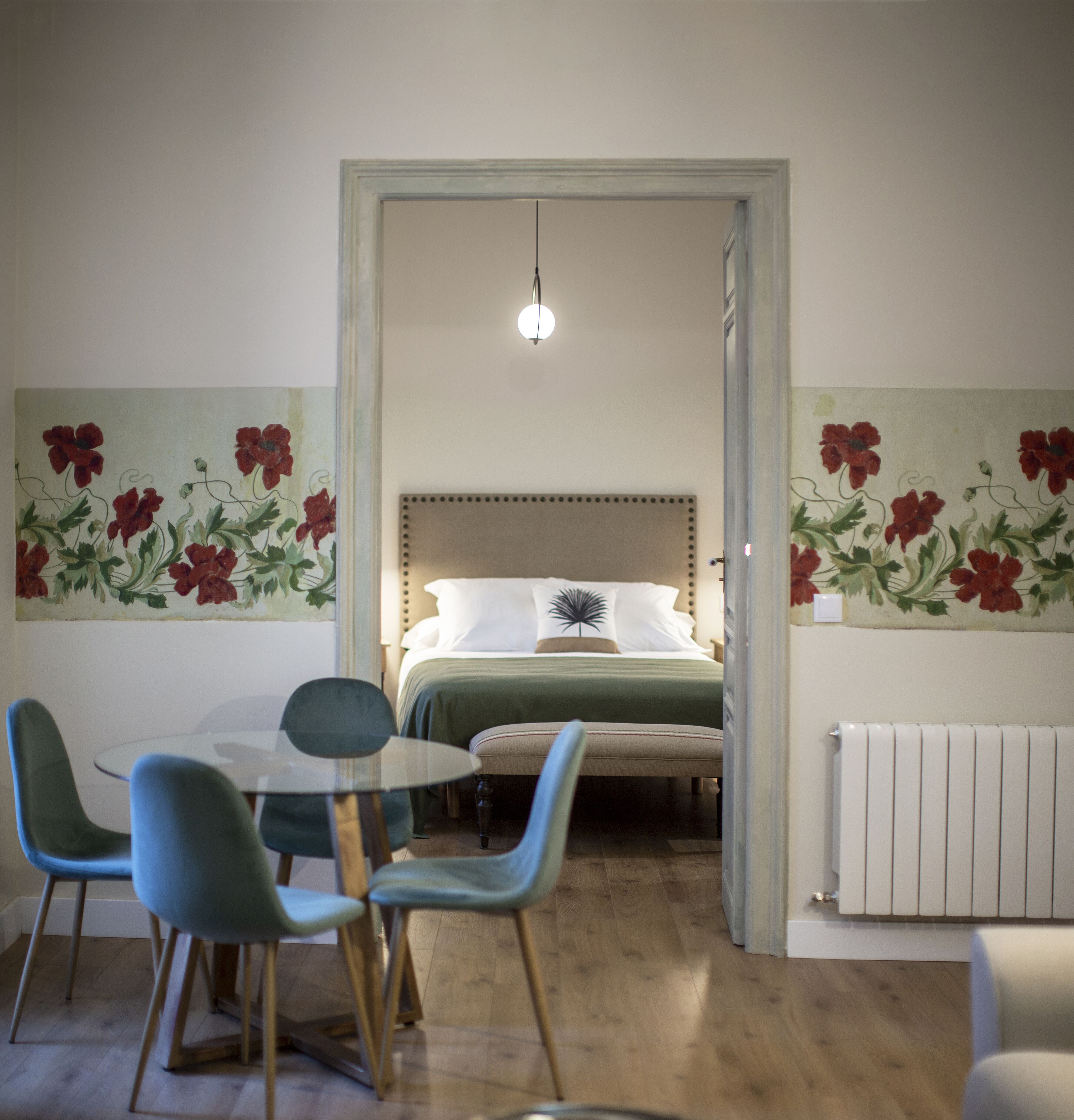 Ein Schlafzimmer mit einem Bett, einem Tisch mit Stühlen und floraler Wandgestaltung.