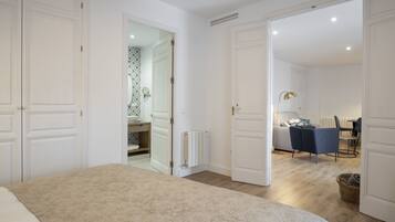 A bedroom with a bed, a bathroom with a mirror and sink, and a dining area with chairs and a table.