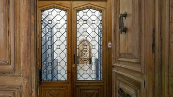 A wooden double door with a decorative glass panel and a metal architrave.