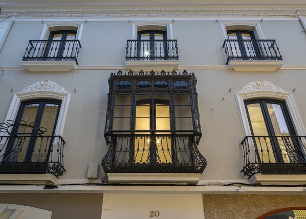 A building with ornate balconies, large windows, and a number '20' sign.