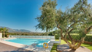 Une piscine équipée d’une bouée de sauvetage, entourée d’une terrasse en bois et d’un grand arbre.