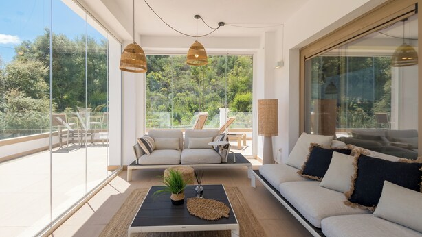 Ein modernes Wohnzimmer mit einer Couch, einem Couchtisch und Blick ins Freie.